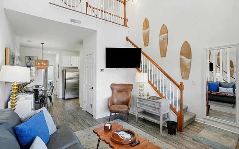 Vaulted living room with surfboard wall, smart TV, and light-filled bay windows