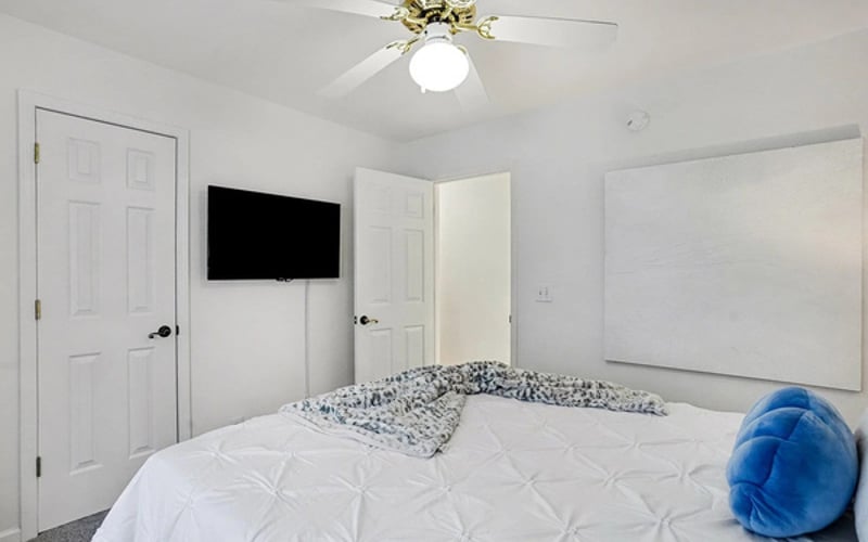 Queen bedroom with wall-mounted smart TV for winding down after the beach