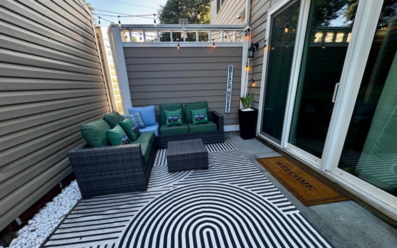 Private outdoor patio with cushioned lounge seating and string lights — golden-hour evenings covered