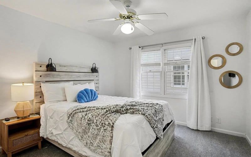 Upstairs queen bedroom with ceiling fan and soft coastal linens